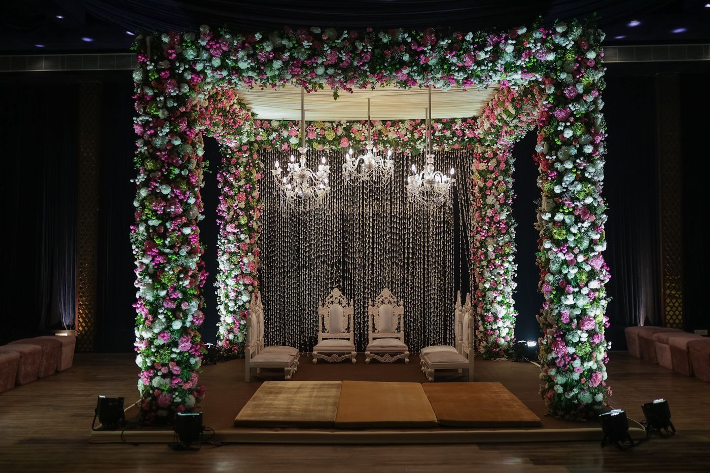 A floral mandap with chandeliers set for the ceremony